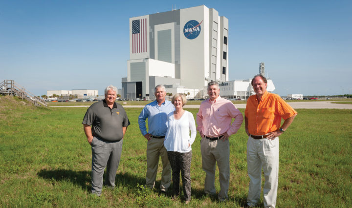 Group of five alumni stand in front of Kennedy Space Center