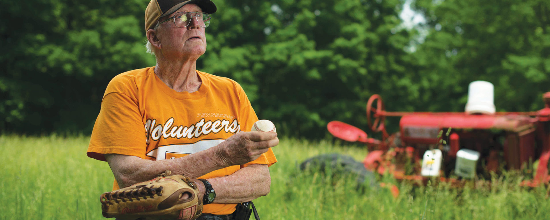 Randall Crowell pictured on his farm in UT orange tshirt, holding a baseball and glove.
