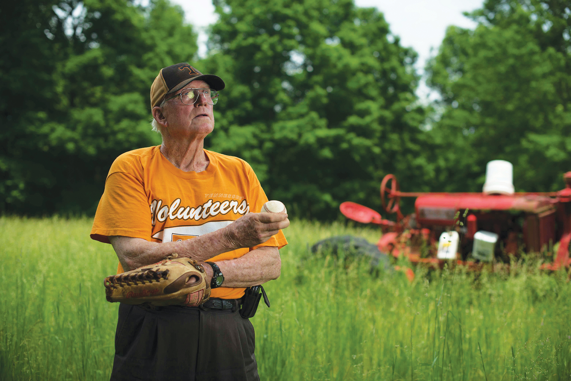 Randall Crowell pictured on his farm in UT orange tshirt, holding a baseball and glove.