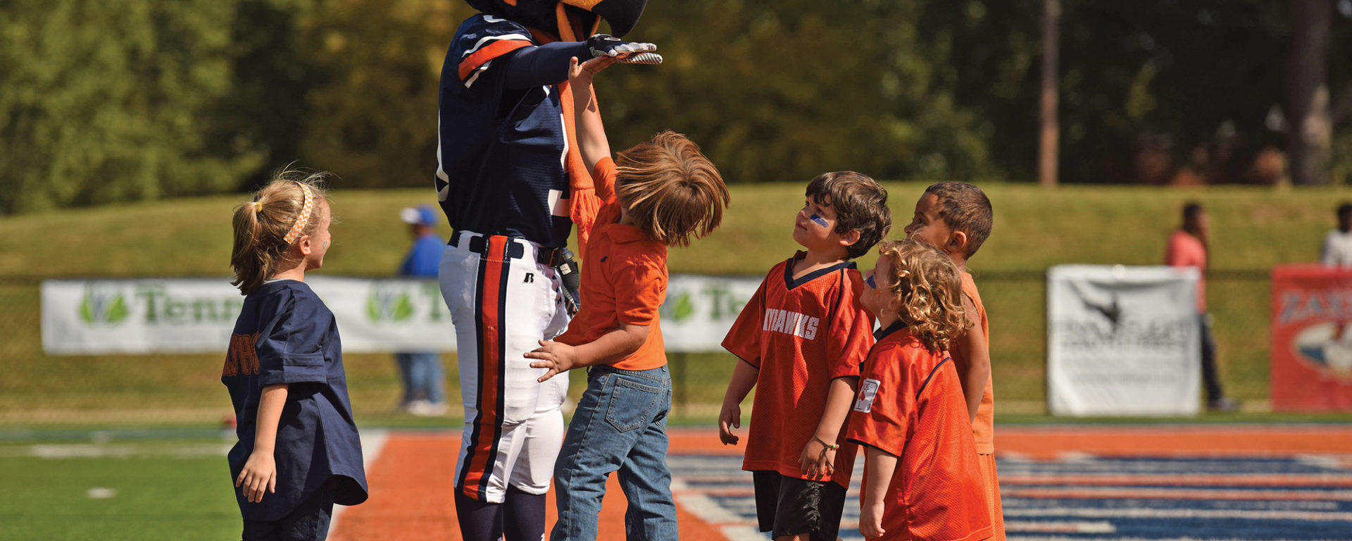 Captain Skyhawk mascot giving high fives to small children