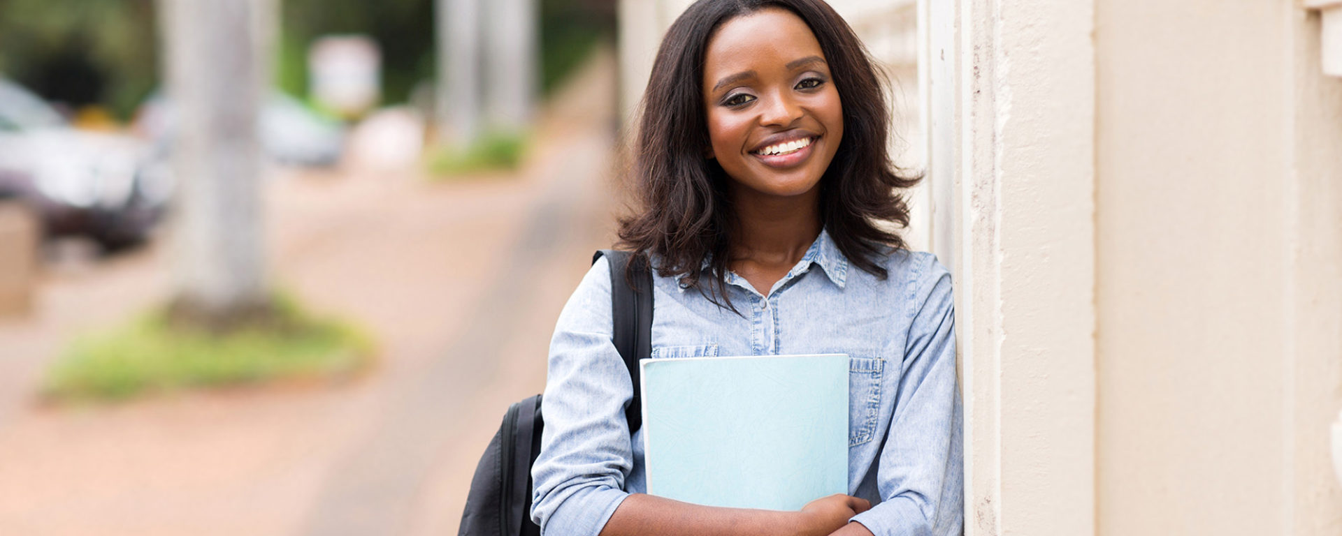 smiling african american young woman holding a book