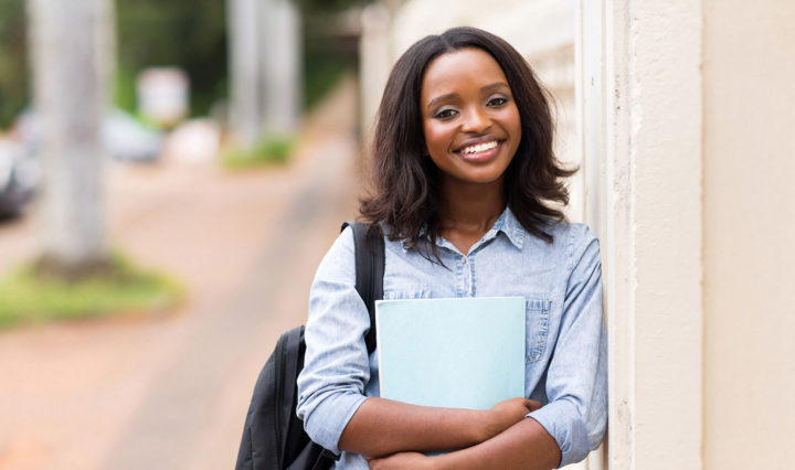 smiling african american young woman holding a book