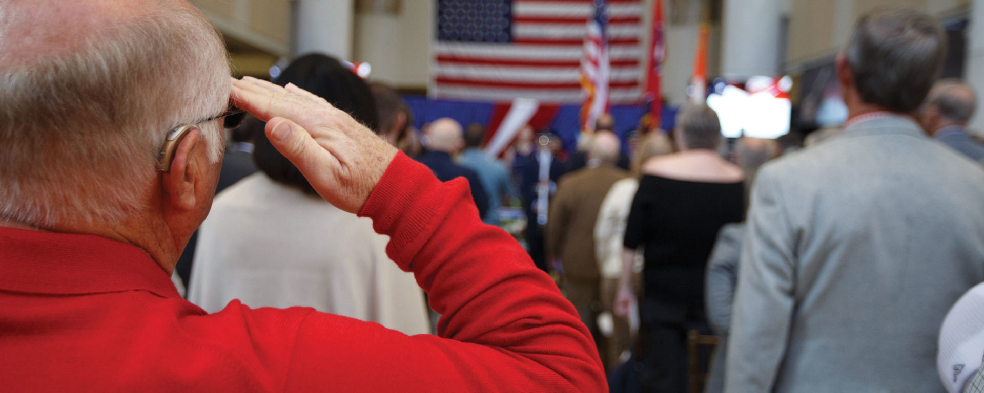An attendee of the grand opening of the UT Knoxville Veterans Resource Center salutes the flag.