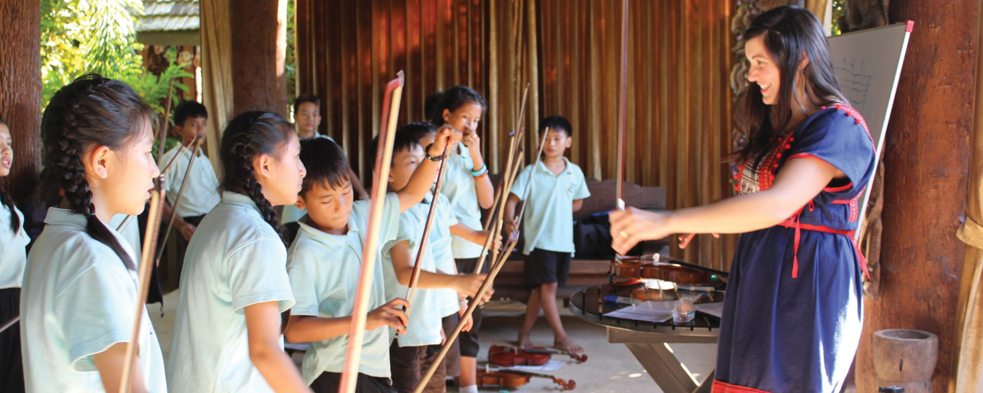 Angela Ammerman teaches Thai children the proper way to hold the violin bow.