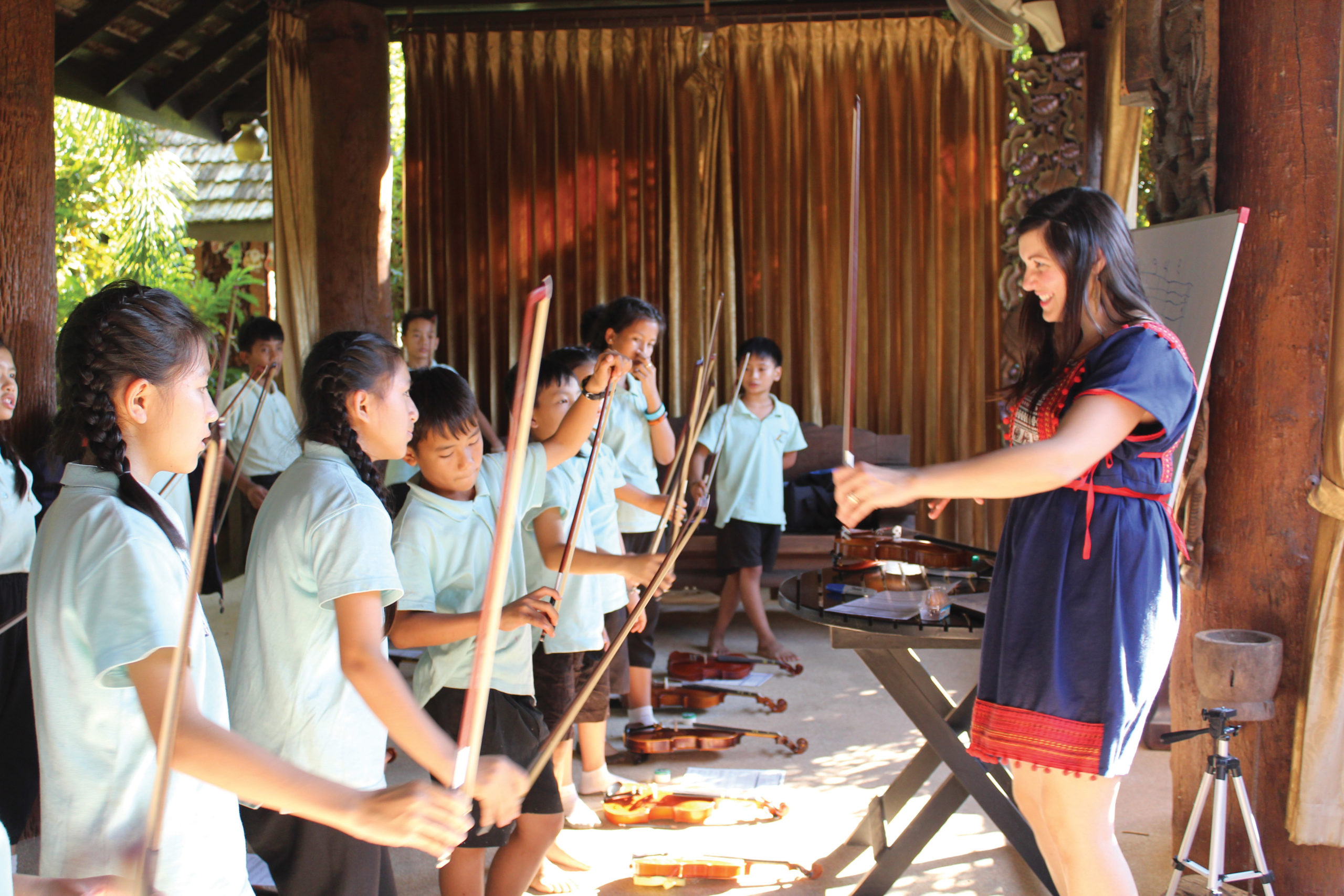 Angela Ammerman teaches Thai children the proper way to hold the violin bow.