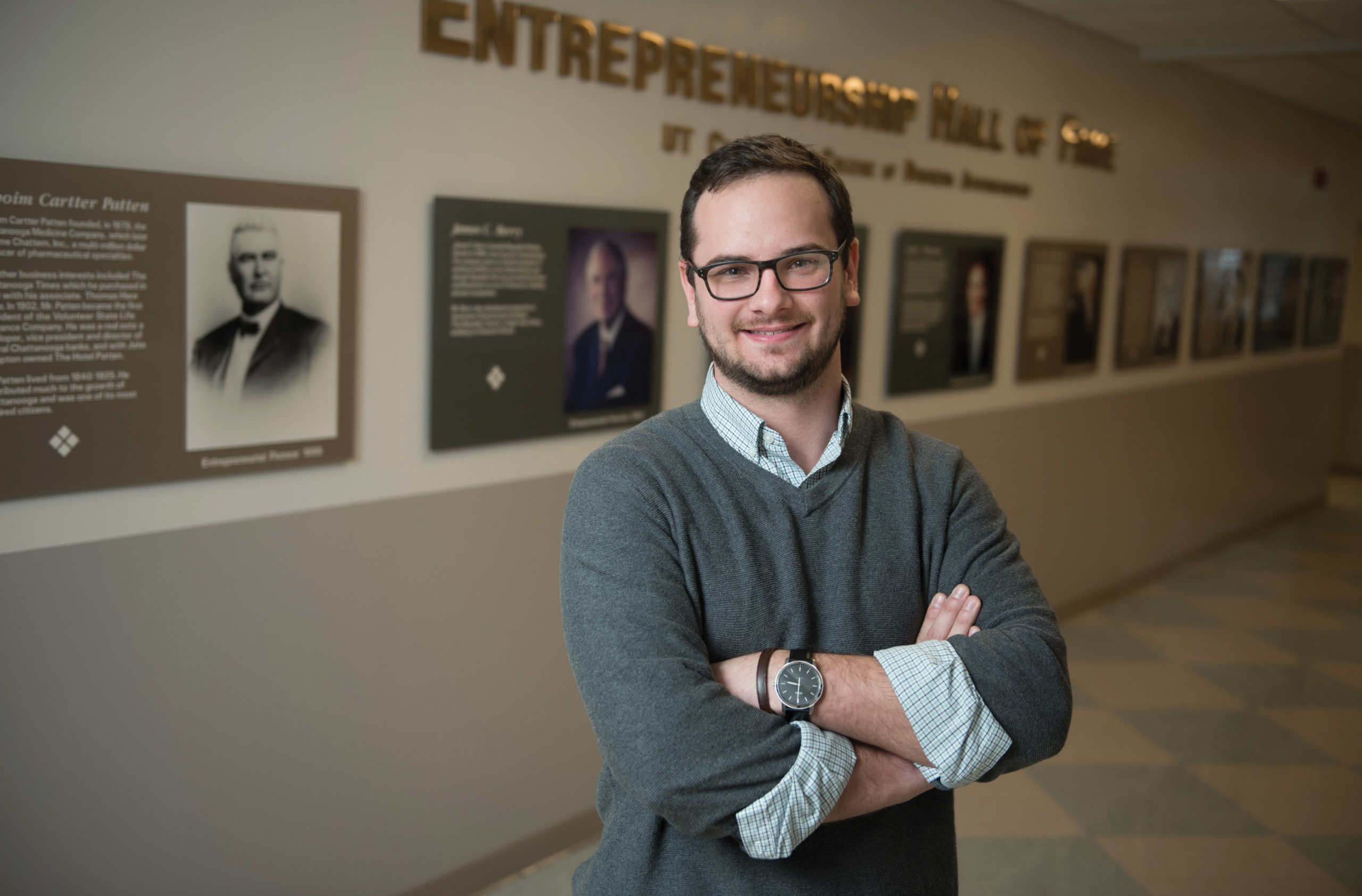 Shane Cotriss stands in front of the Entrepreneurship Wall of Fame at UTC