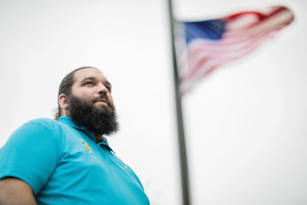 Michael Johnson, a student veteran at UT Martin stands under the American flag at half-mast