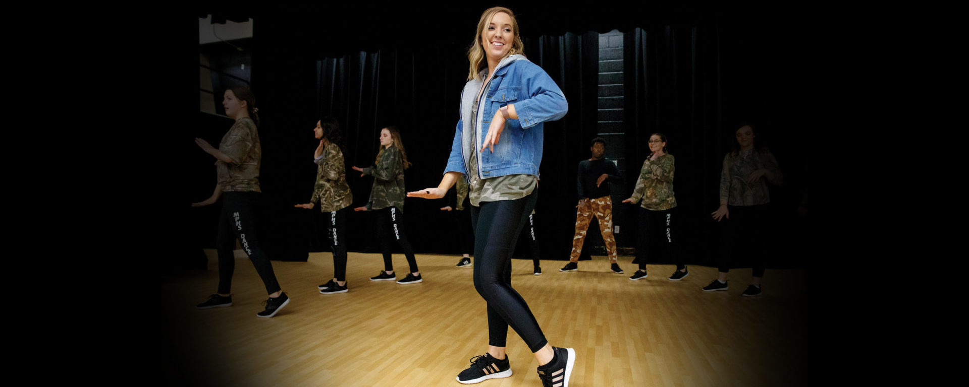 Abby Murphy points her left toe, instructing a row of dance students behind her