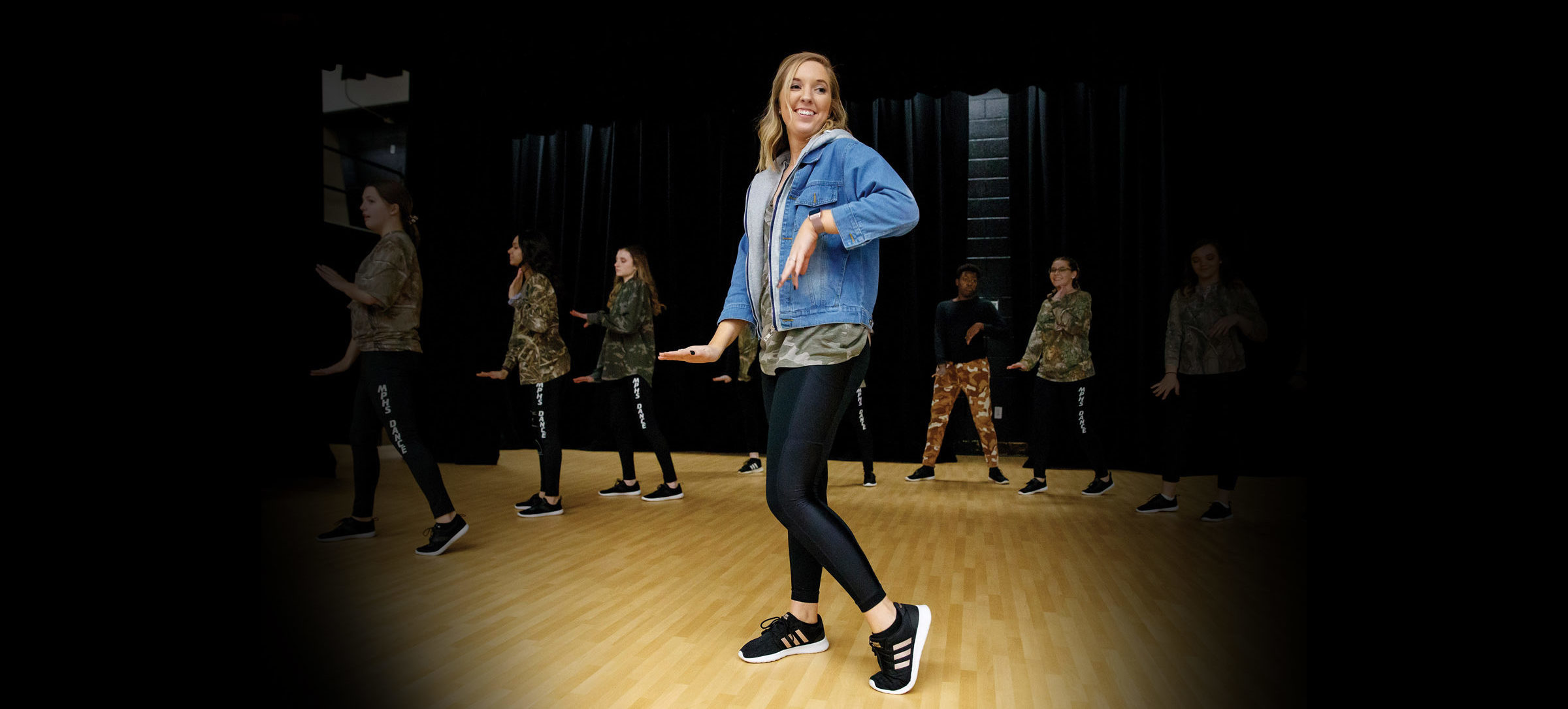 Abby Murphy points her left toe, instructing a row of dance students behind her