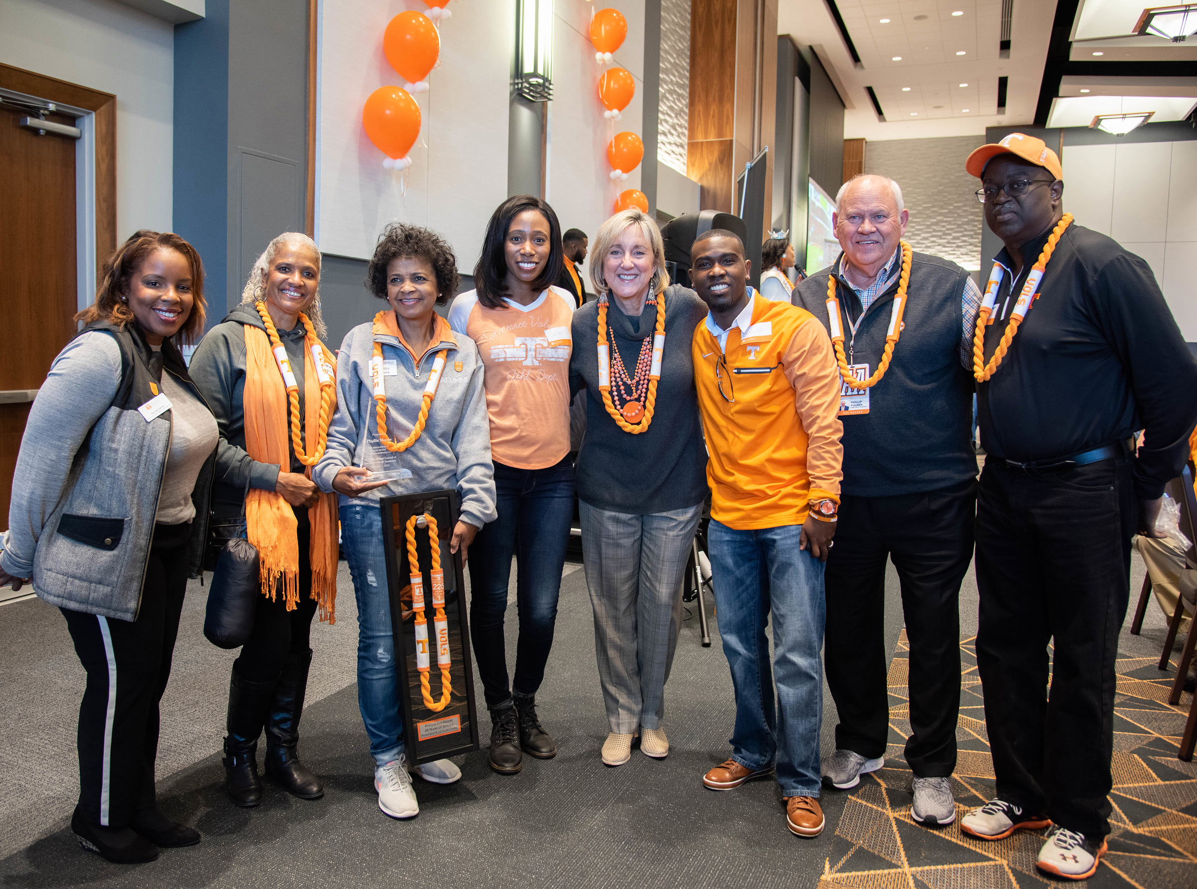 a group of alumni and administrators dressed in orange, white and smokey gray