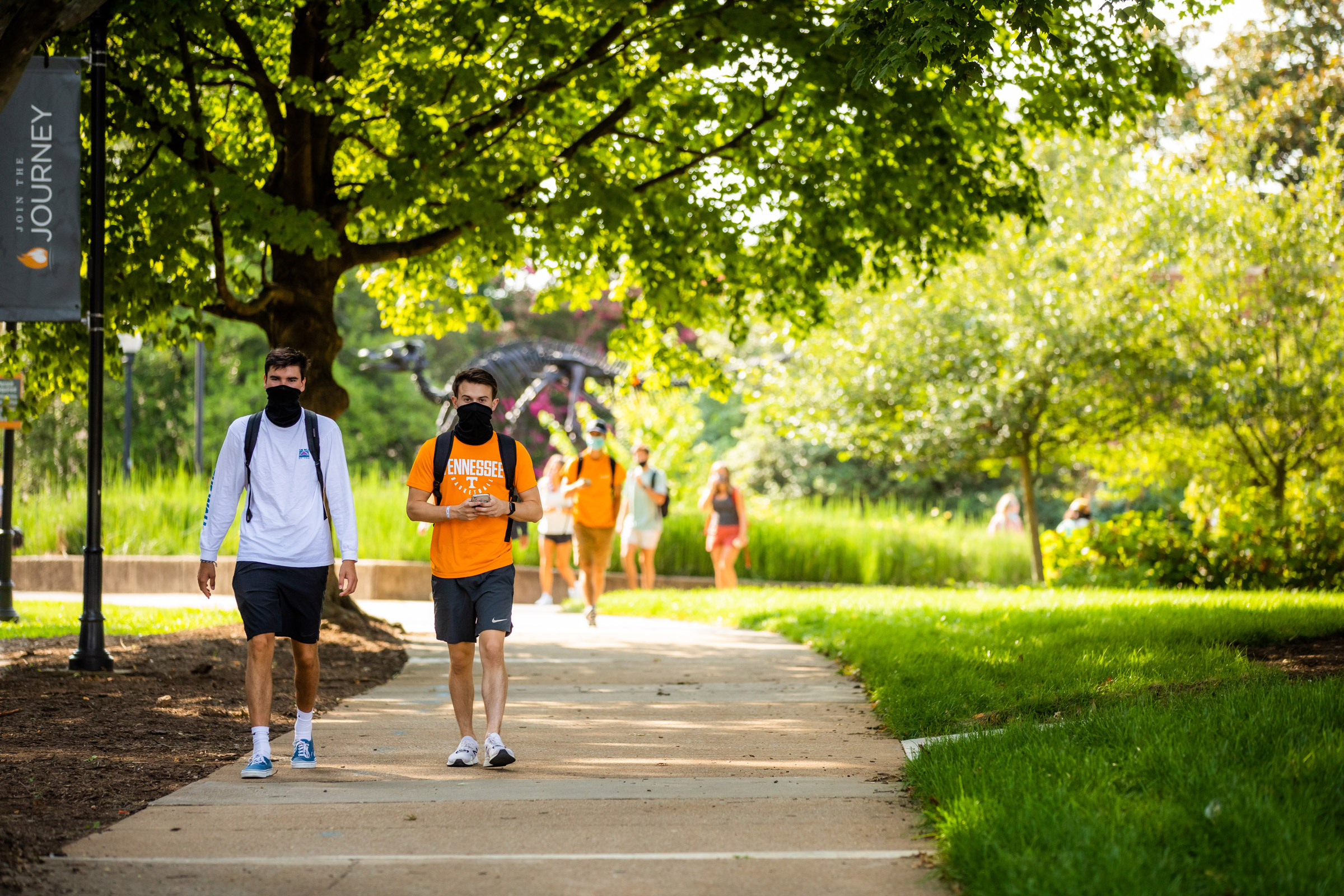 Two young men walk through Circle Park on their way to the Communication or Student Services Building