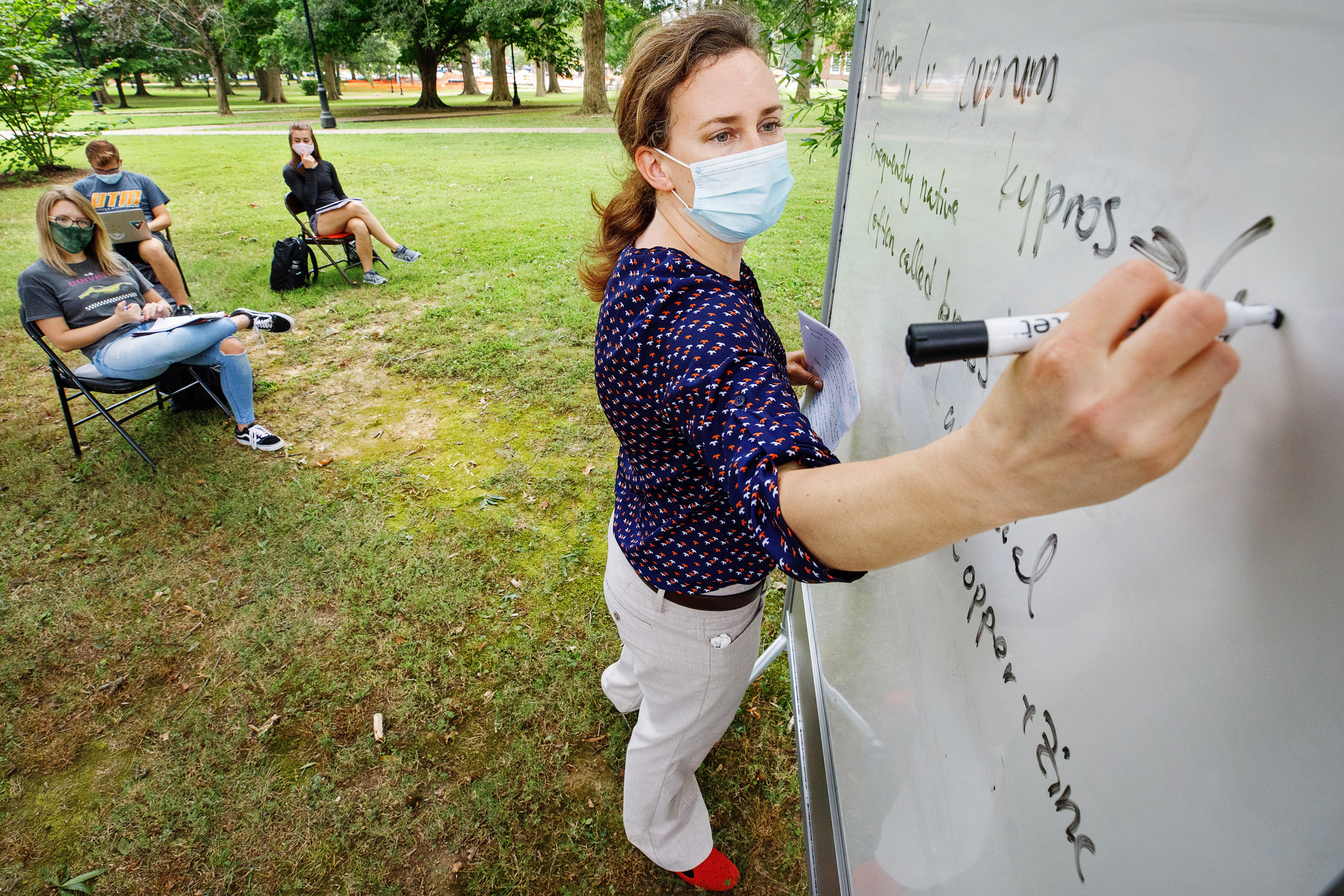 A chemistry lecturer writes on a dry erase board outside on the UTM Quad