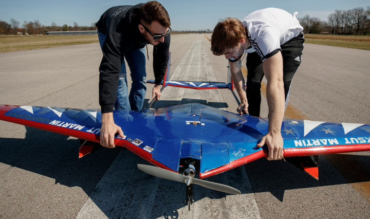 Two young men position a small aircraft on a test runway