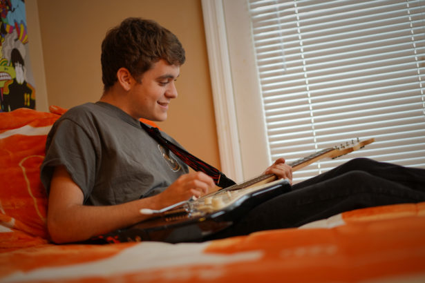 Ben Kredich plays an electric guitar in his bedroom
