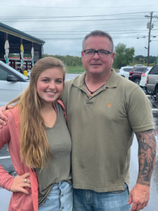 A father and daughter photographed together in a parking lot