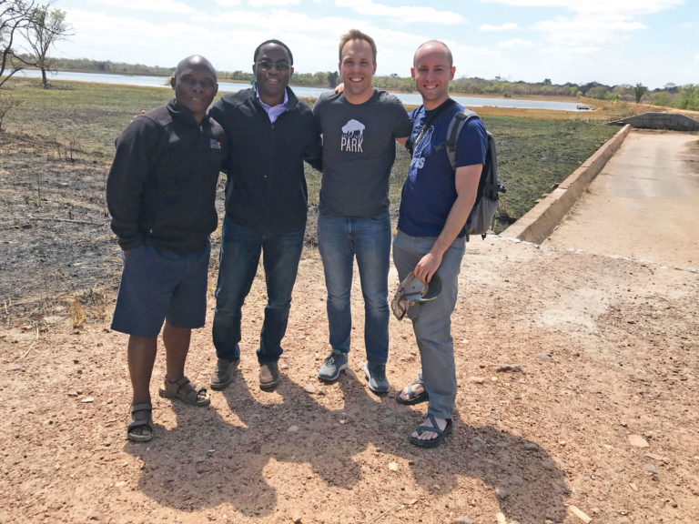 A group of four men stand together for a photo outdoors in Zambia