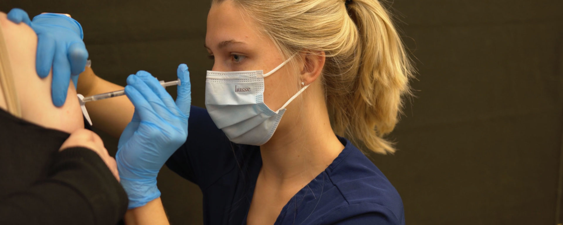 A blonde UTC nursing student gives the Covid vaccine to a patient