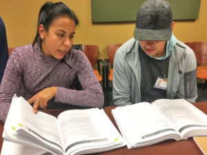 Two students collaborate with their textbooks open