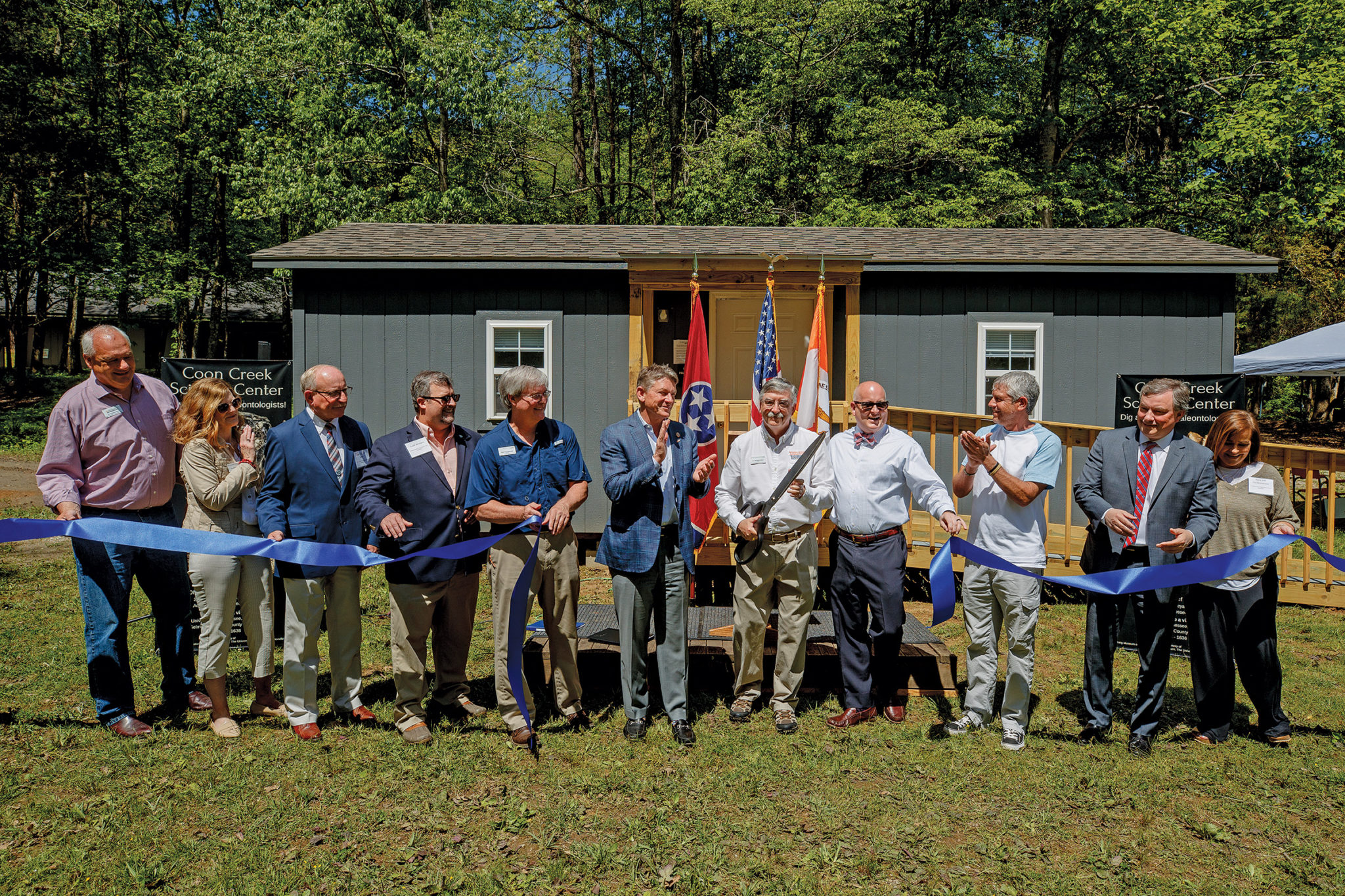 officials cut a ribbon in front of a small building