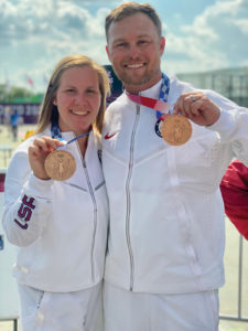 A woman and a man dressed i white Team USA track suits hold their bronze medals in Tokyo