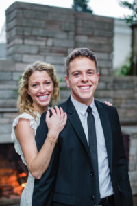 Troy Galyon with his wife Sarah on their wedding day in front of an outdoor fireplace