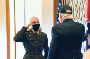 A young female ROTC cadet salutes an older male Vietnam War veteran