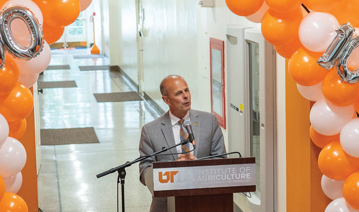 Tim Cross speaks at a podium surrounded by orange and white balloons