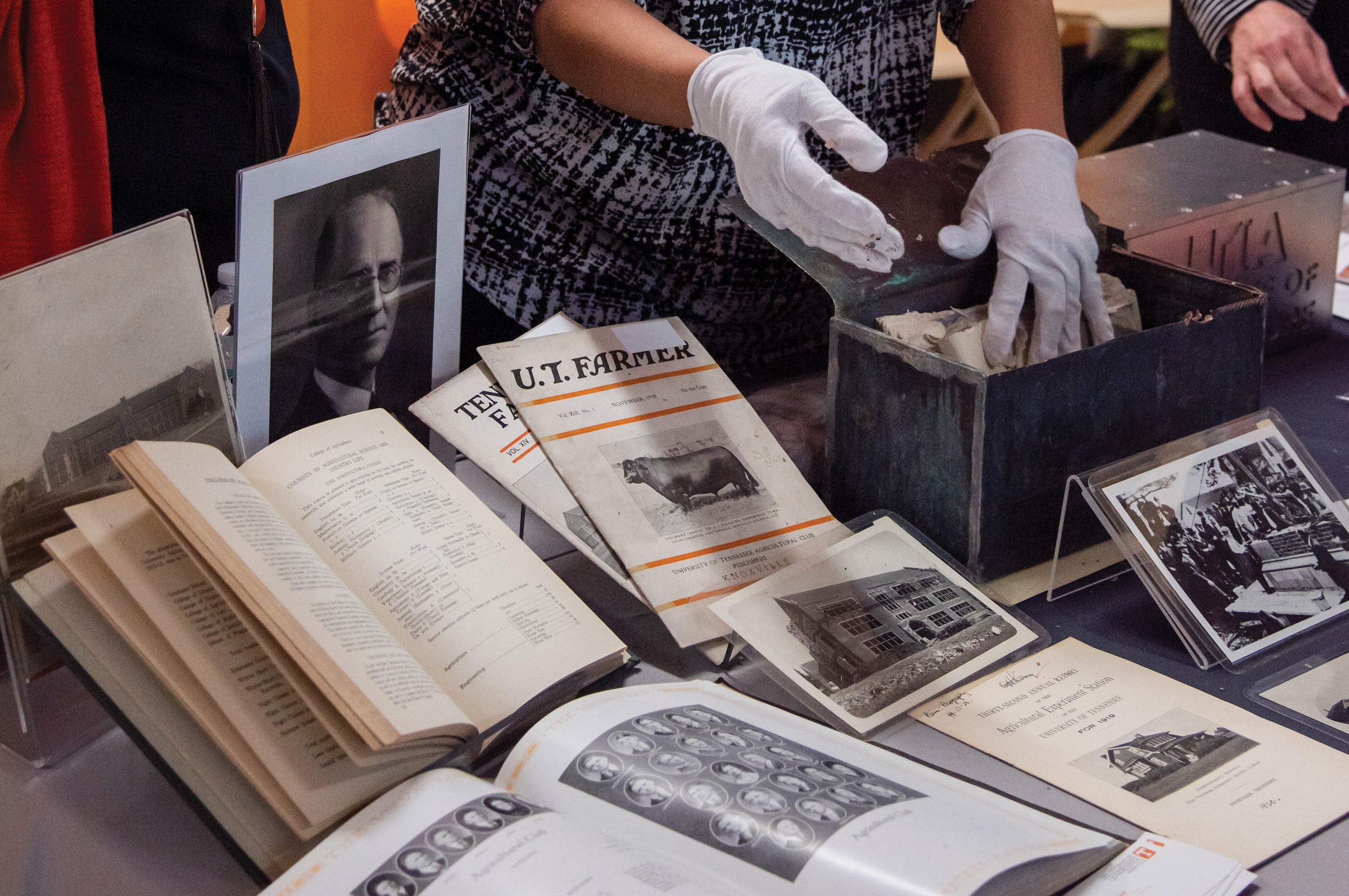 Two gloved hands carefully hande documents from 1919 unsealed from a time capsule