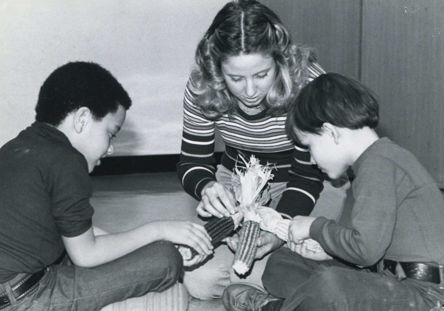 A woman works with two boys on a hands on learning activity