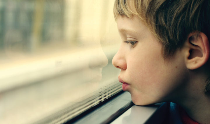A boy looks out a bus or train window