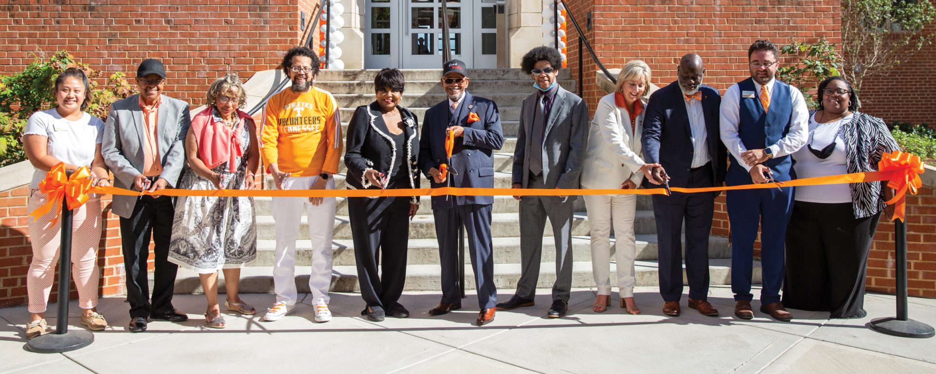 A group of students, alumni and officals cut the ribbon in front of two UT residence halls