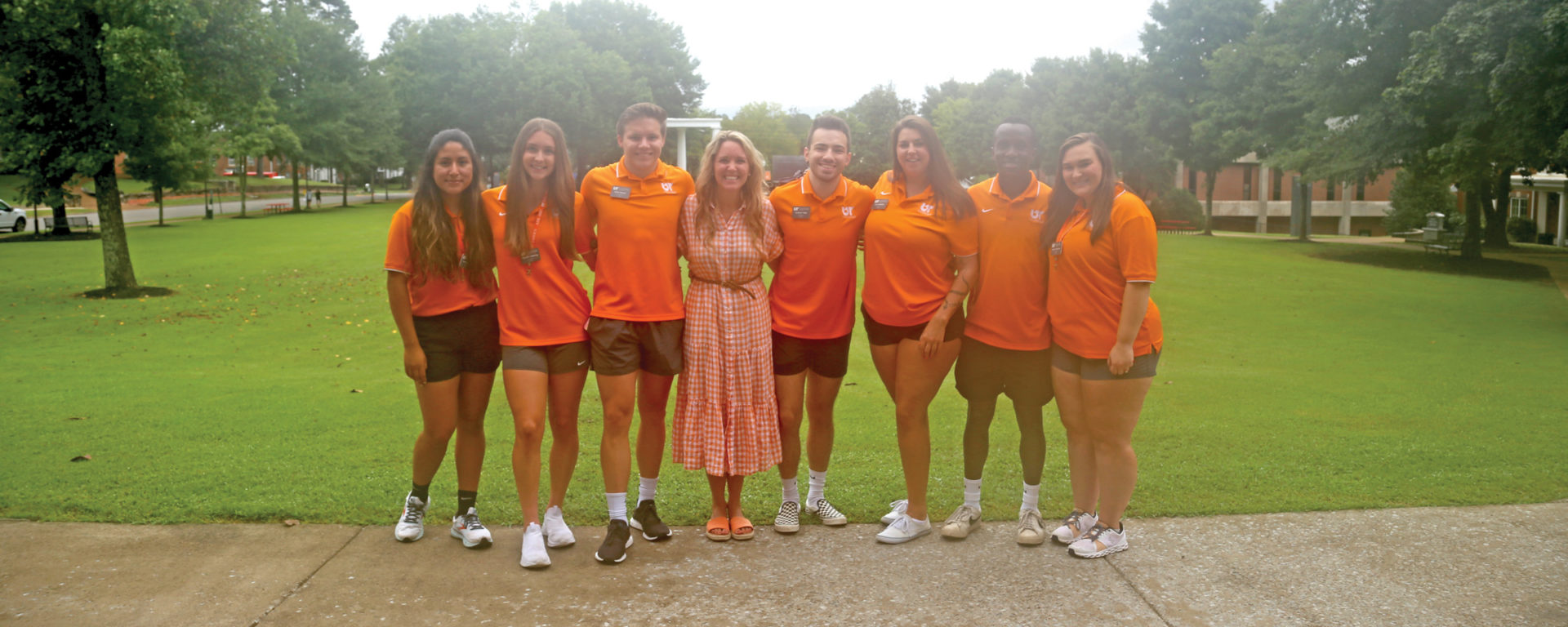 Director of student life Sarah Catherine Richardson with a group of seven students at UT Southern all dressed in orange