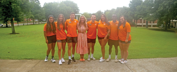 Director of student life Sarah Catherine Richardson with a group of seven students at UT Southern all dressed in orange