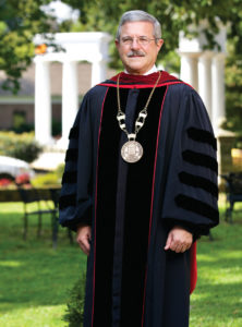 A middle aged man in doctoral robes and regalia