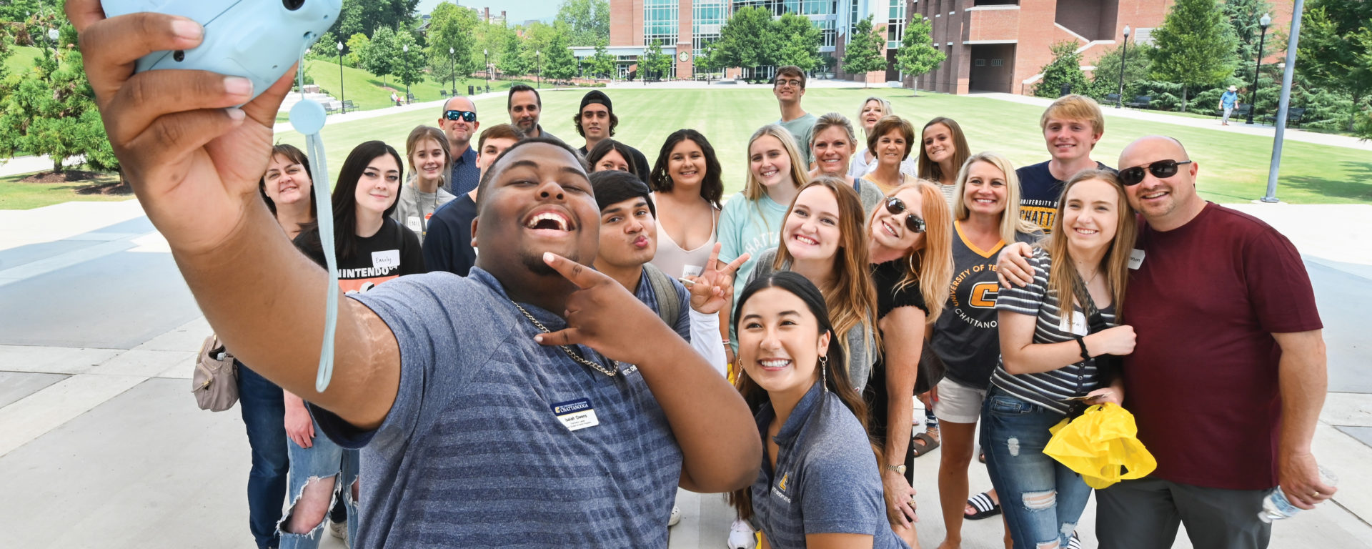 An orientation leader takes a group selfie with a crowd on UTC's campus