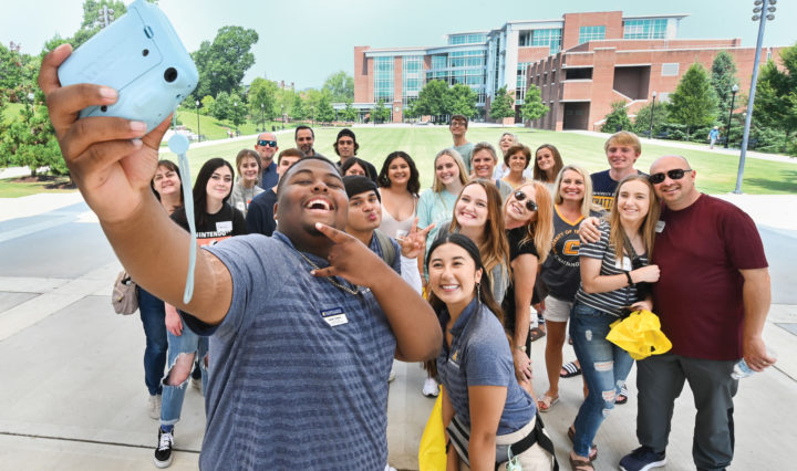 An orientation leader takes a group selfie with a crowd on UTC's campus