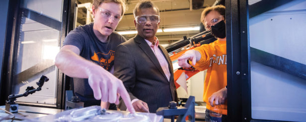 Suresh Babu, center, works with students on the MELD Machine inside the Machine Tool Research Center.