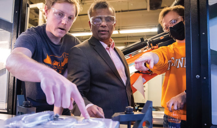 Suresh Babu, center, works with students on the MELD Machine inside the Machine Tool Research Center.