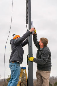 Tickle College of Engineering senior Hans Perry, left, and Signal Power President Doug Zukowski fasten an access point to a Signal Power Hybrid Light Tower. 