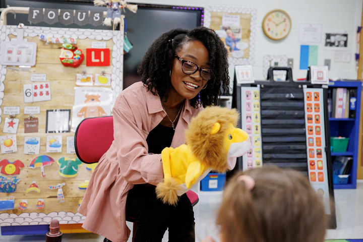 Teacher Michaela Frederick (Martin ’17, ’22) holing a lion puppet while teaching a class.