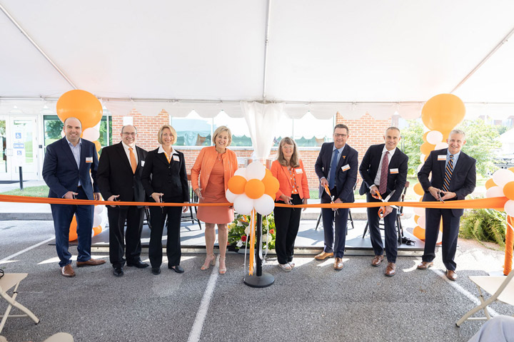Leadership from the University of Tennessee and Eastman celebrate the Eastman Innovation Center's opening by cutting an orange ribbon made from high-tech material. 
