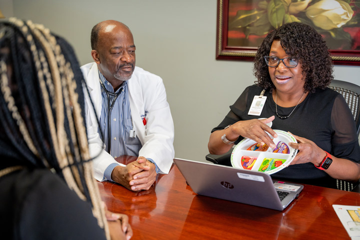 Dr. Stanley Dowell and Brenda Riddle discuss heart-healthy practices with a patient.