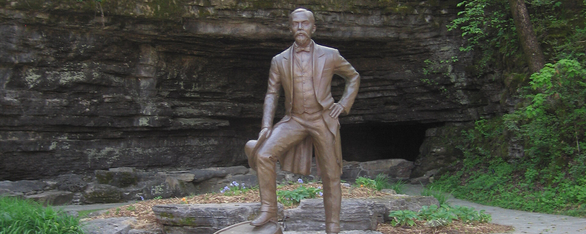 Jack on the Rocks statue in front of the Cave Spring opening at the Jack Daniel Distillery.