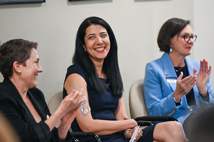 Mina Sartipi, executive director of the UTC Research Institute, talks and smiles with two women during a meeting.