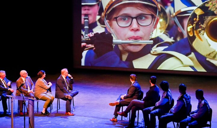 Representatives from the London Parade office, the city of London and UTC representatives watch footage of the London Parade in the Hayes Concert Hall before presenting the Marching Mocs with its official invitation to participate in the London New Year’s Day Parade.