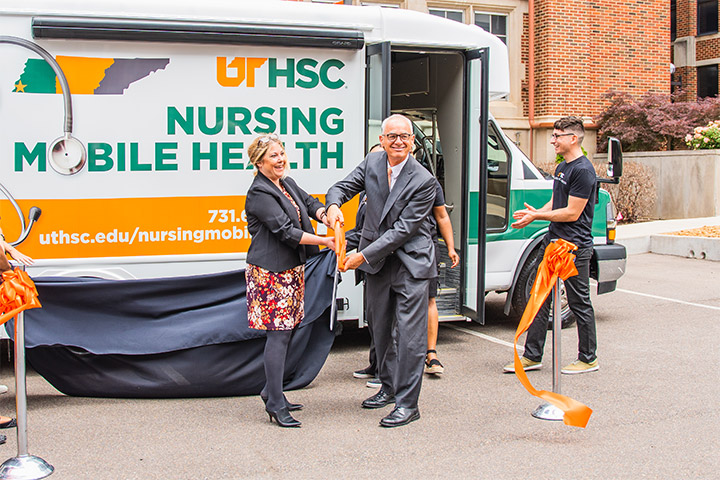 UTHSC Chancellor Peter Buckley cuts the ribbon at the unveiling ceremony of a mobile health unit.
