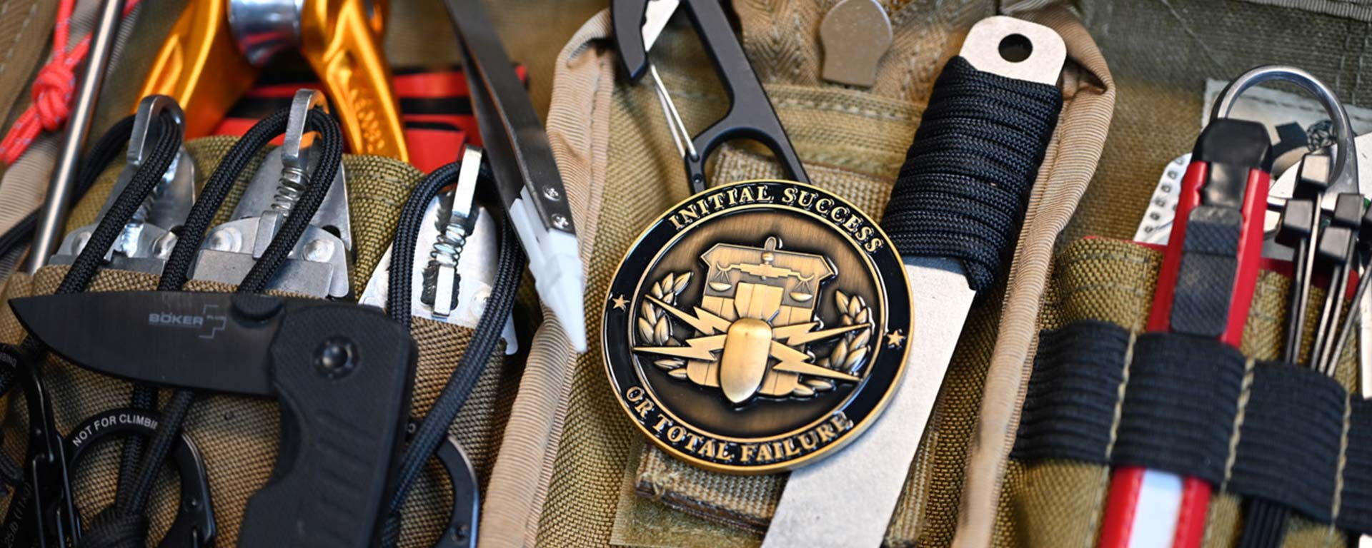 Military themed challenge coin alongside assorted pieces of military gear.