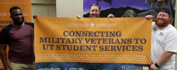 UT Knoxville students and military veterans display a banner which reads "Connecting military veterans to UT student services".