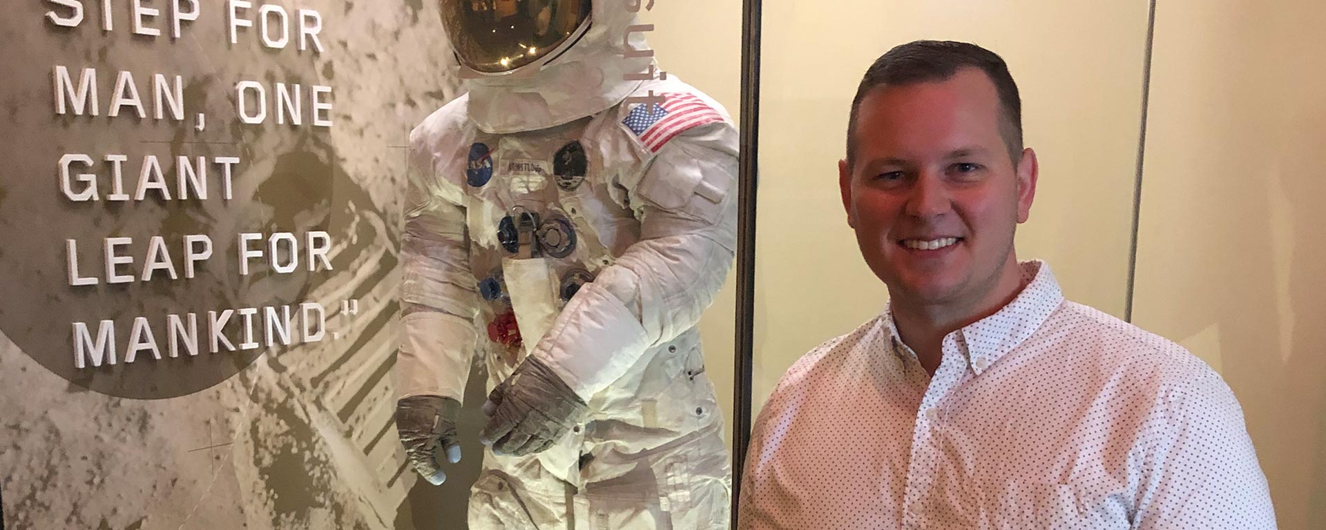 Aaron Bolen standing next to an astronaut suit exhibit.