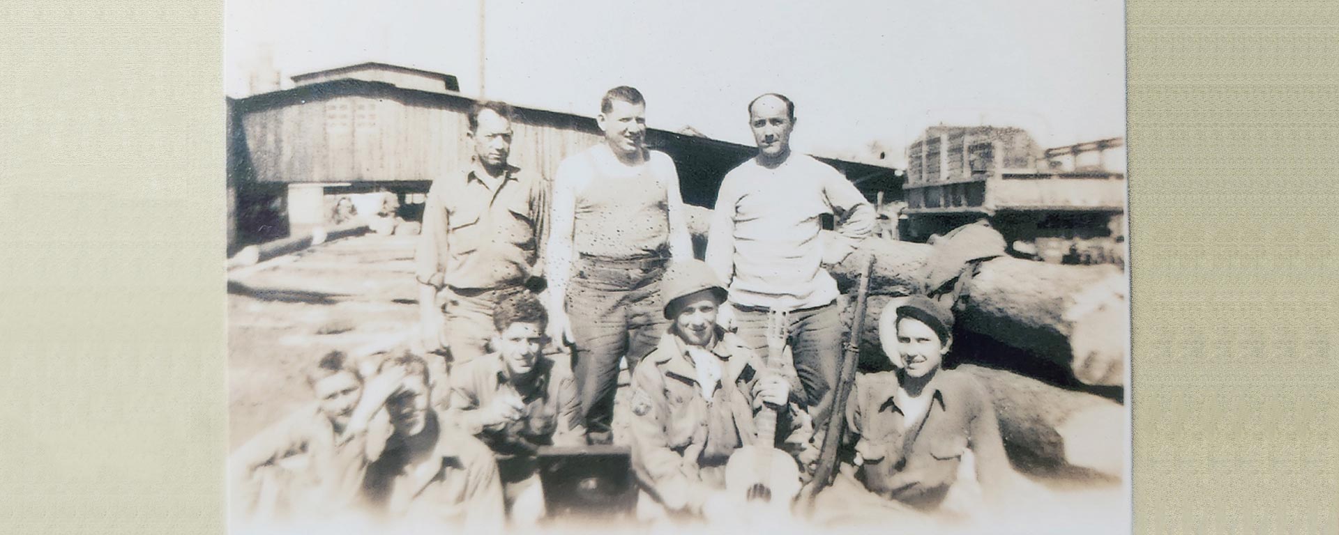 Old photo of T Joe Walker, holding guitar, with other soldiers during World War II.